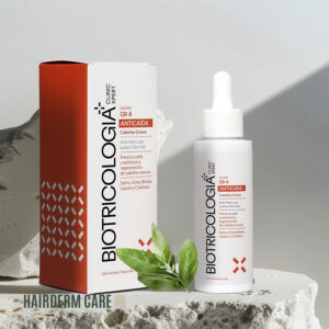 Loción capilar anticaída GR-8 de Biotricologia+ para cabellos grasos, mostrada junto a su caja en un entorno natural con una planta verde al fondo. El envase blanco con dosificador destaca los ingredientes activos como salvia, ginkgo biloba, lupulo y calabaza, diseñado para prevenir la caída del cabello y estimular la regeneración capilar